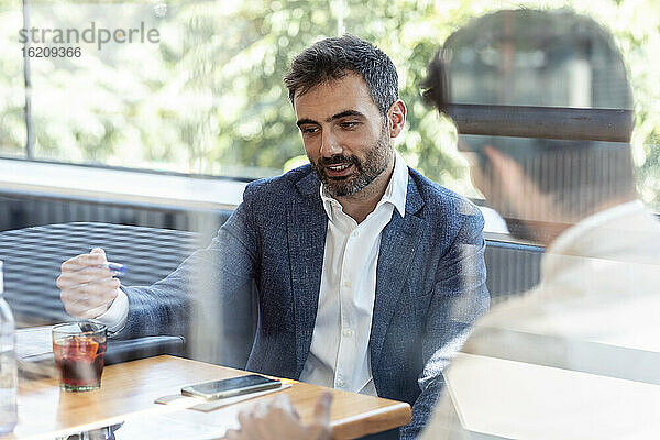 Geschäftsmann im Gespräch mit einem männlichen Kollegen während eines Treffens in einem Café