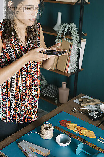 Junge kreative Frau  die ein Smartphone-Foto von einer Dekoration auf dem Tisch macht