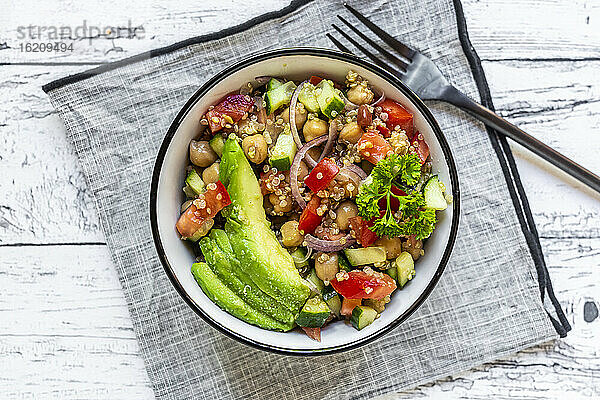 Schüssel mit vegetarischem Quinoa-Salat mit Kichererbsen  Avocado  Gurke  Tomate  Zwiebel und Petersilie