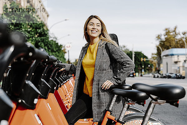 Junge Frau mit Geigenkasten mietet Fahrrad in der Stadt