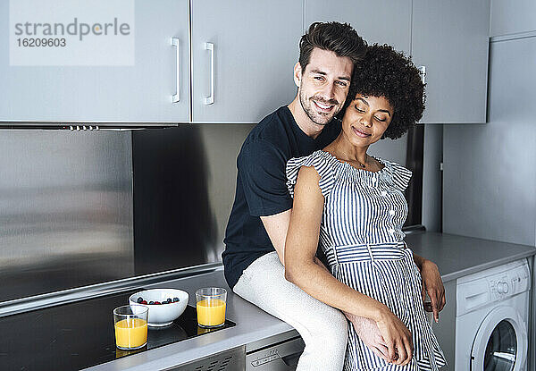 Liebevolles multiethnisches Paar in der modernen Küche eines Penthouse