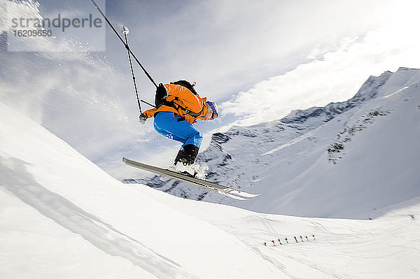 Österreich  Mann springt mit Ski auf Berg