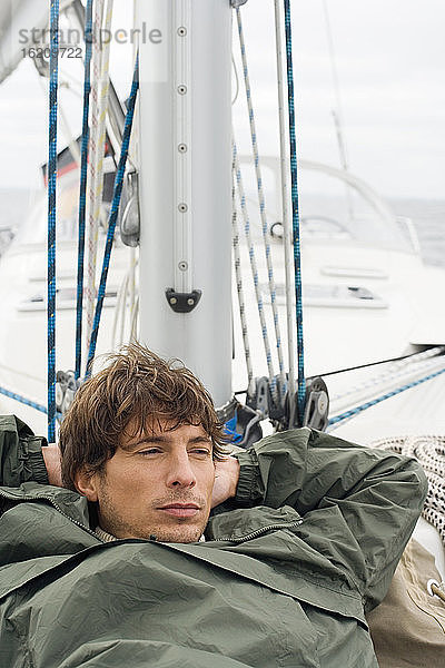 Deutschland  Ostsee  Lübecker Bucht  Junger Mann auf Deck einer Yacht liegend  Porträt