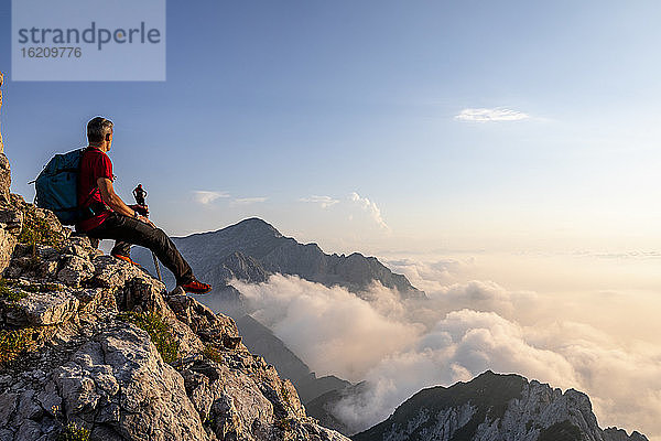 Wanderer bewundert die Aussicht  während er auf dem Gipfel eines Berges in den Bergamasker Alpen  Italien  sitzt