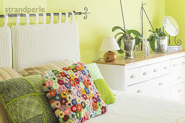 Schlafzimmerbett mit buntem Blumenkissen