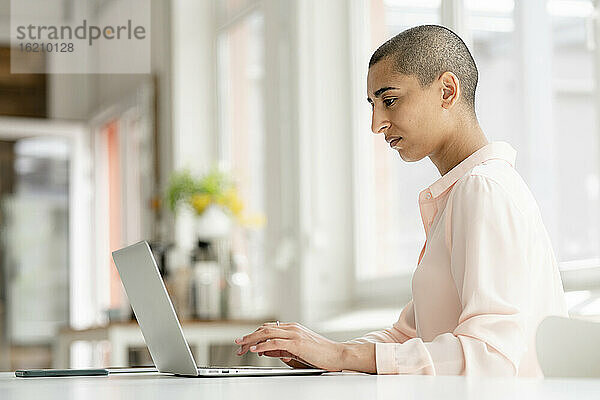 Konzentrierte Geschäftsfrau mit Laptop am Schreibtisch im Loftbüro