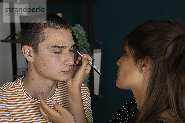 Junge Frau trägt Make-up auf einen Mann auf