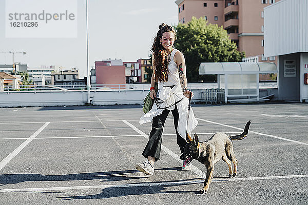 Frau geht mit Hund auf einem Parkplatz spazieren