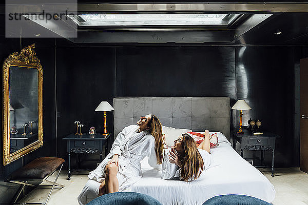 Schwestern  die durch ein Oberlicht schauen  während sie sich auf einem Bett in einer Ferienanlage entspannen