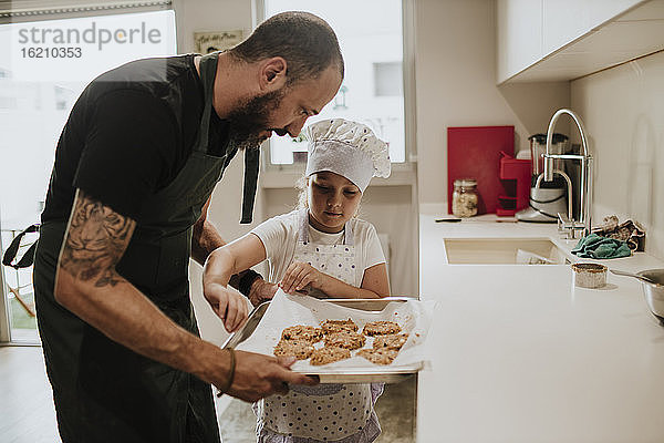Vater und Tochter backen Kekse zu Hause
