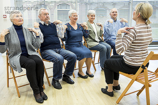 Gruppe von Senioren bei der Stuhlgymnastik mit einem Lehrer in einem Seniorenheim