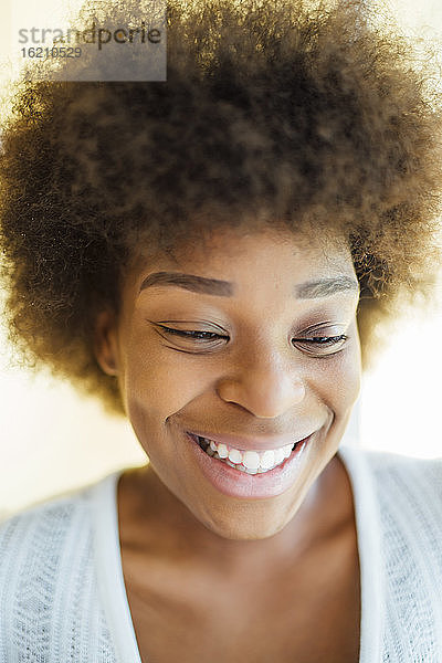 Nahaufnahme einer lächelnden Frau mit Afro-Haar  die auf ihr Zuhause blickt