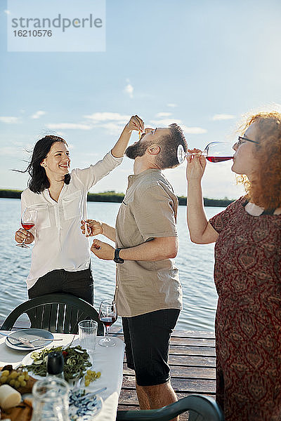 Glückliche Freunde beim Abendessen am See und beim Weintrinken