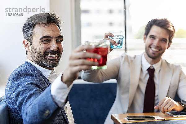 Fröhliche Geschäftsleute jubeln  während sie in einem Café etwas trinken