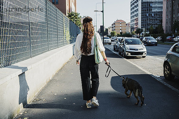 Frau mit Hund auf dem Gehweg in der Stadt
