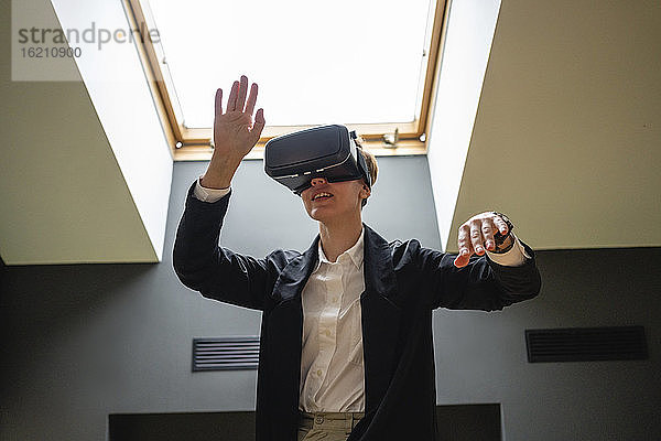 Geschäftsfrau gestikuliert  während sie ein Virtual-Reality-Simulator-Headset im Büro trägt