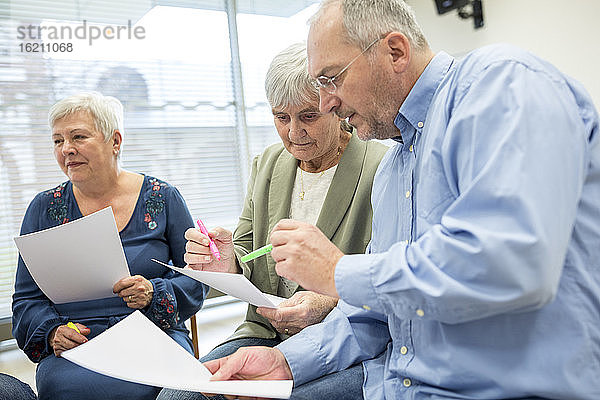 Senioren in einer Therapiegruppe in einem Seniorenheim  die Notizen auf Zetteln notieren