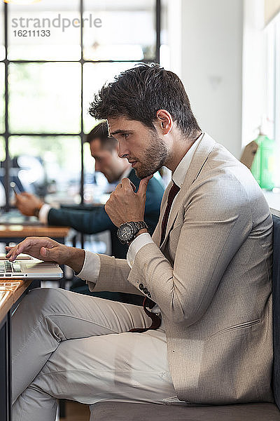Geschäftsmann denkt bei der Benutzung eines Laptops im Restaurant