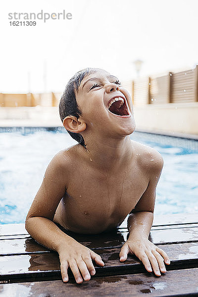 Fröhlicher Junge  der am Pool aufsteht