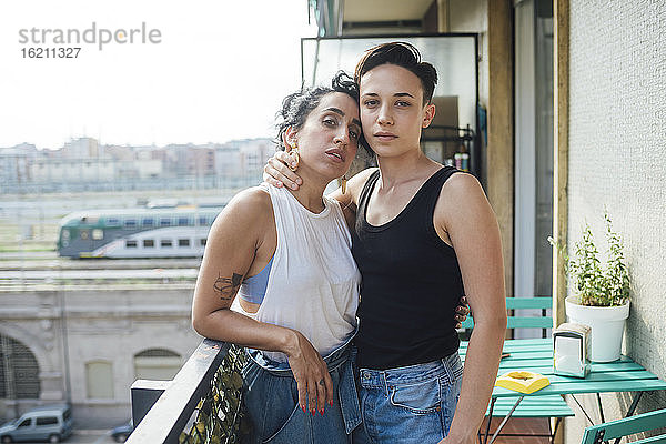 Lesbisches Paar auf dem Balkon stehend mit Arm um Arm