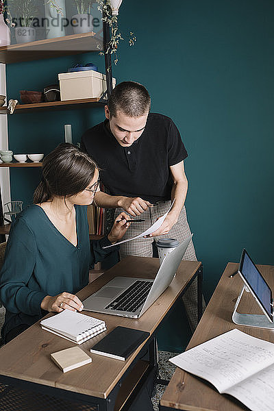 Junger Mann und Frau besprechen Papier im Heimbüro