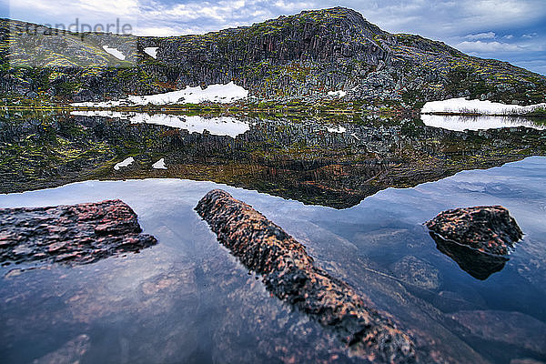 Hügel  die sich im klaren Küstenwasser der Barentssee spiegeln