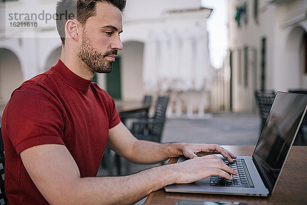 Mann mit Laptop auf Tisch in der Stadt