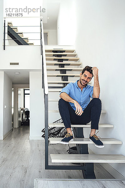 Glücklicher Mann sitzt auf einer schwebenden Treppe in einem modernen Penthouse