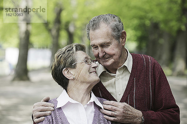 Deutschland  Köln  Älteres Paar sieht sich im Park lächelnd an