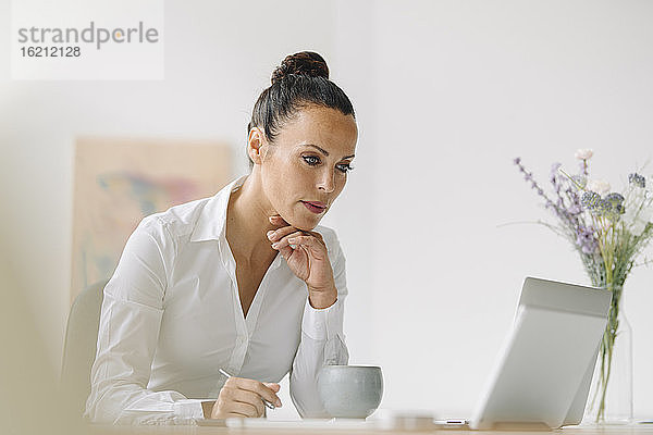 Geschäftsfrau  die auf einen Laptop schaut  während sie an einem Schreibtisch im Heimbüro arbeitet