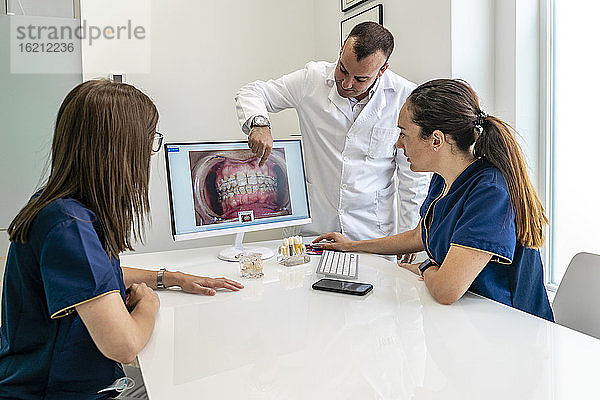 Zahnärztin im Gespräch mit Ärztinnen beim Betrachten von Röntgenbildern in der Klinik