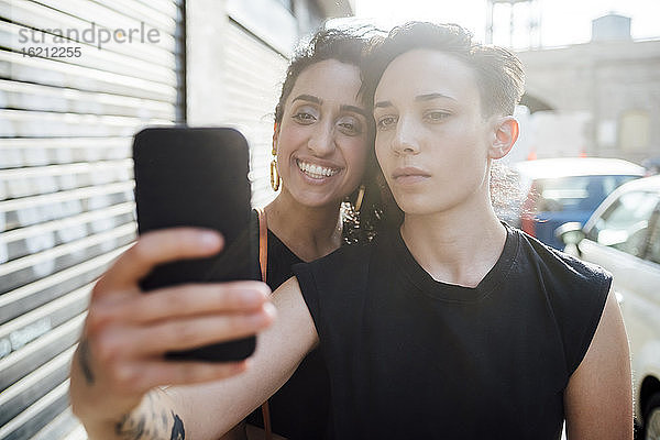 Lächelnde Frau und Partner nehmen Selfie in der Stadt