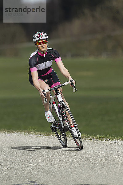 Deutschland  Bayern  Mittlere erwachsene Frau fährt Rennrad