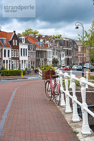 Niederlande  Nordholland  Haarlem  Fahrrad am Geländer der Kanalbrücke geparkt  mit Häusern entlang der Straße Hooimarkt im Hintergrund