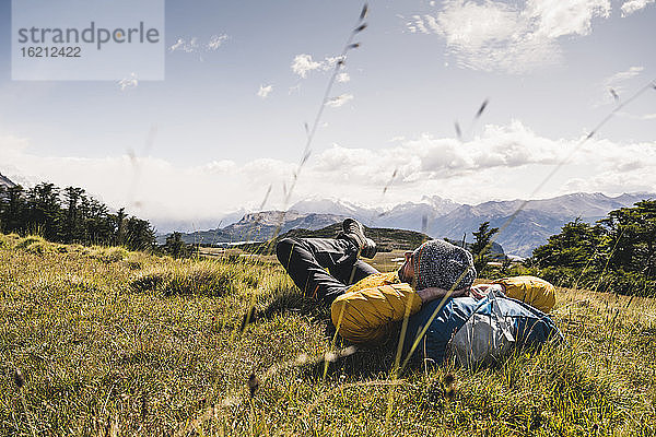 Mann mit Händen hinter dem Kopf  der auf einem Berg in Patagonien  Argentinien  Südamerika  ruht
