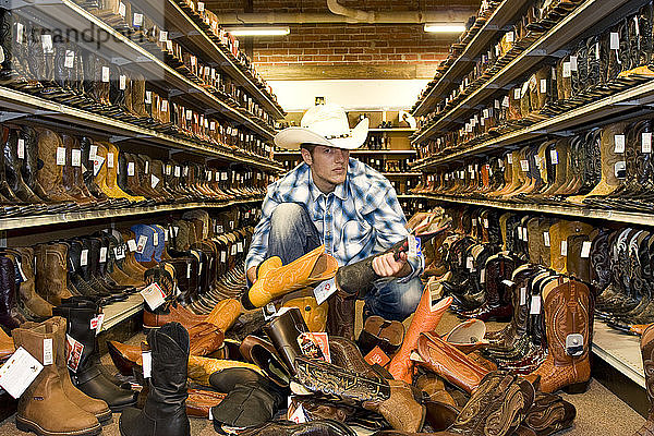 USA  Texas  Dallas  Junger Mann sucht Cowboystiefel in einem Schuhgeschäft aus