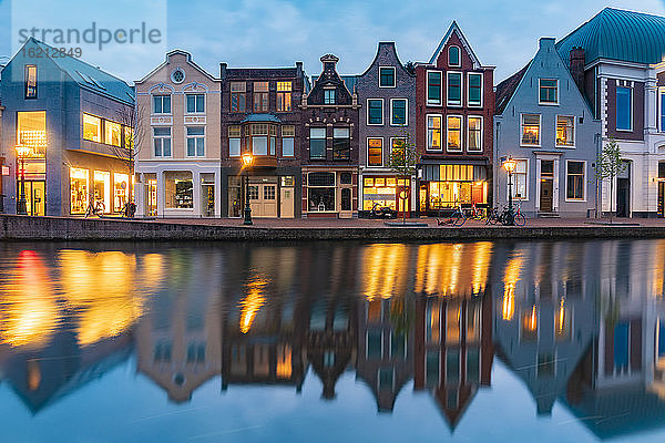 Niederlande  Südholland  Leiden  Reihe historischer Stadthäuser  die sich in der Abenddämmerung im Rheinkanal spiegeln