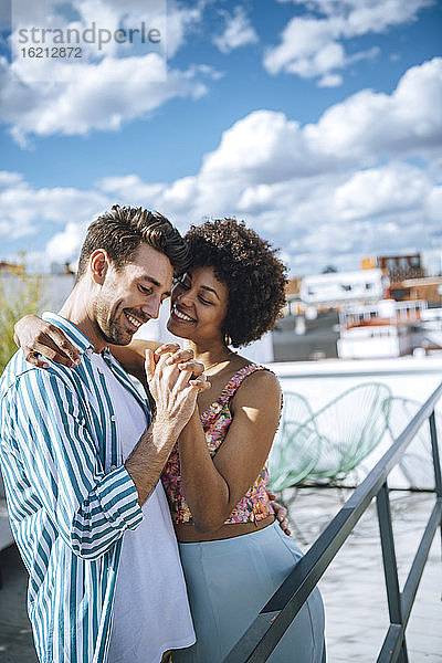 Glückliches multiethnisches Paar tanzt auf der Penthouse-Terrasse