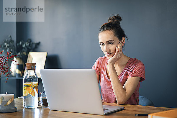 Unternehmerin mit Laptop auf dem Schreibtisch an der Wand im Heimbüro