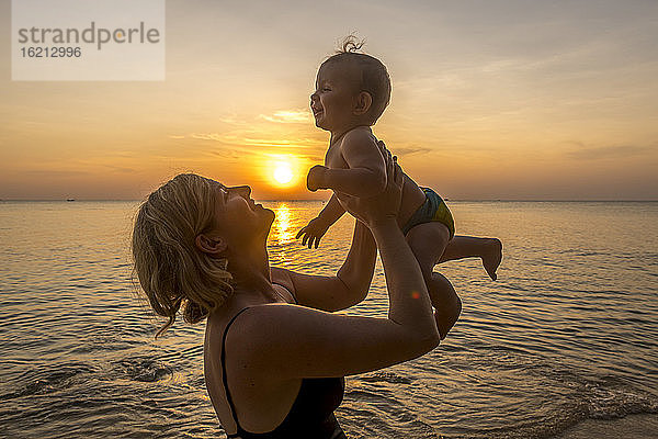 Vietnam  Insel Phu Quoc  Ong Lang Strand  Mutter hält Baby am Strand bei Sonnenuntergang