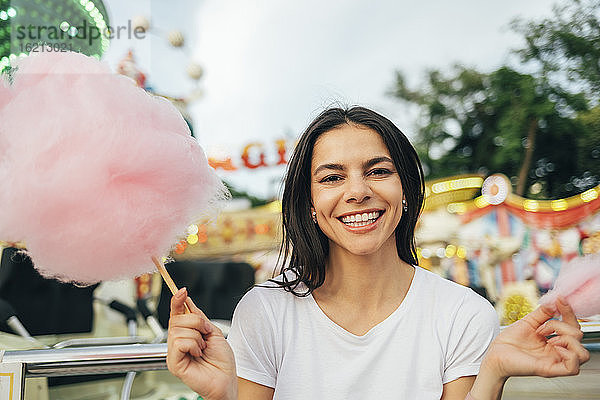 Lächelnde schöne Frau mit Zuckerwatte im Vergnügungspark