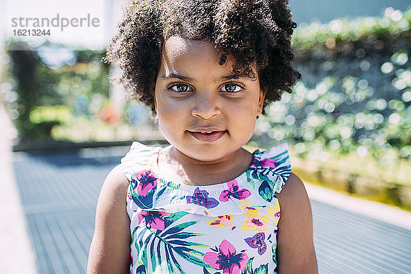 Close-up-Porträt von niedlichen Baby-Mädchen mit lockigem Haar stehen im Freien