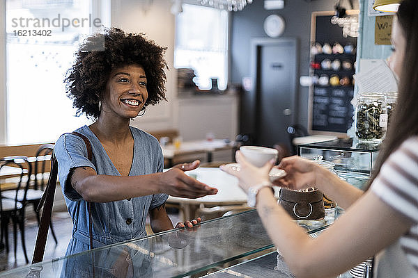 Glückliche Frau nimmt Kaffee vom Besitzer in einem Café