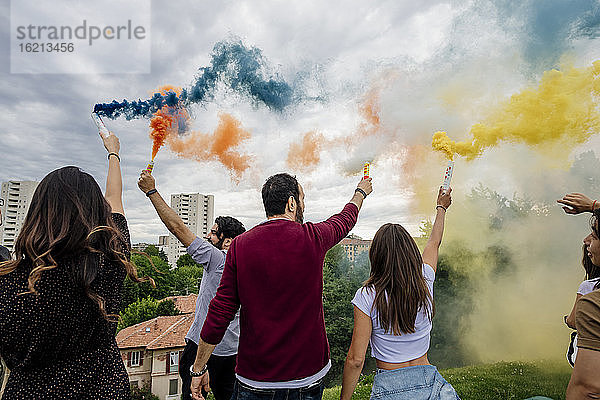 Männliche und weibliche Freunde spielen mit Rauchbomben im Park am Wochenende