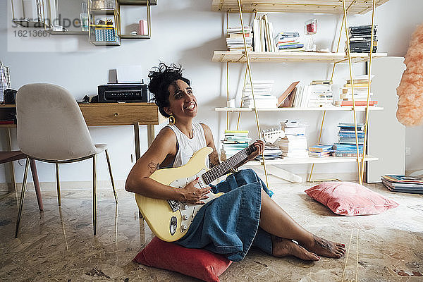 Frau spielt Gitarre im Wohnzimmer
