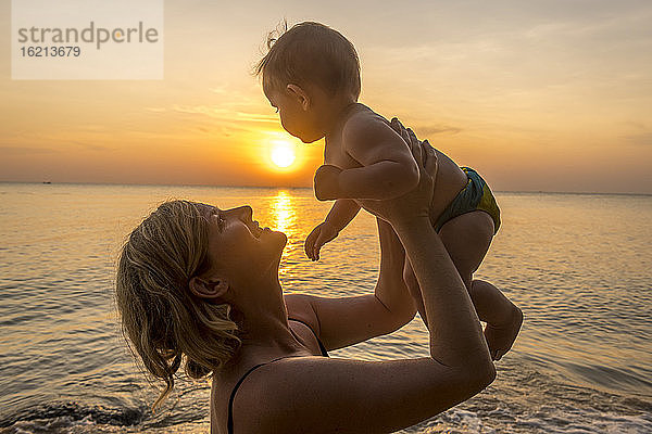 Vietnam  Phu Quoc Insel  Ong Lang Strand  Mutter hält Baby am Strand bei Sonnenuntergang