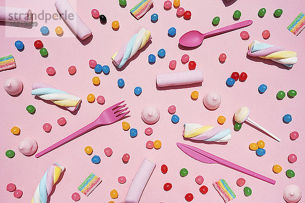 Verschiedene Süßigkeiten vor rosa Hintergrund