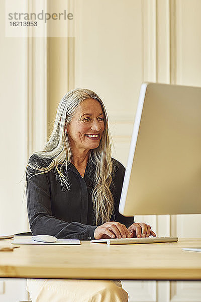 Lächelnde Geschäftsfrau  die zu Hause am Computer arbeitet