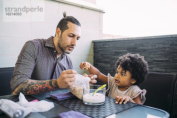 Vater und Tochter mit Essen und Milch auf dem Esstisch zu Hause
