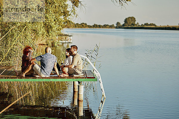 Freunde beim Picknick auf dem Steg eines Sees